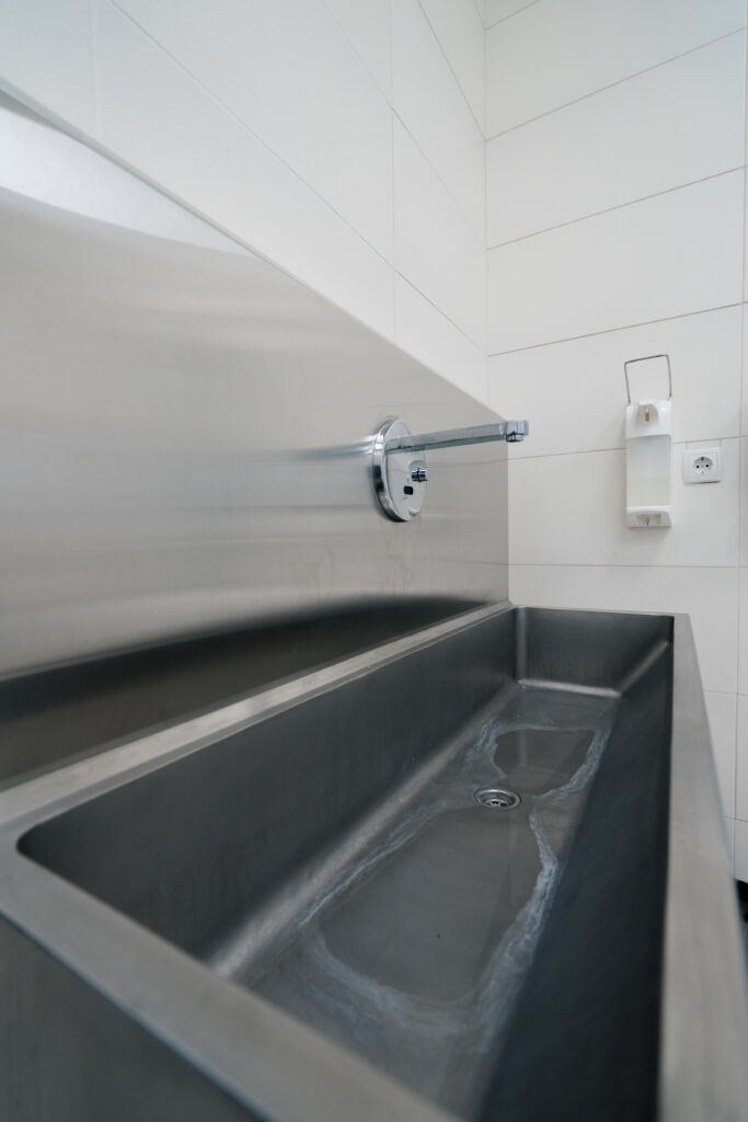 Stainless steel trough sink with a wall-mounted tap